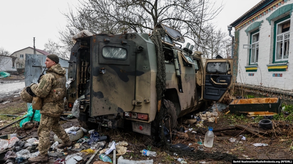Një ushtar ukrainas shihet pranë një automjeti të blinduar të braktisur nga rusët.