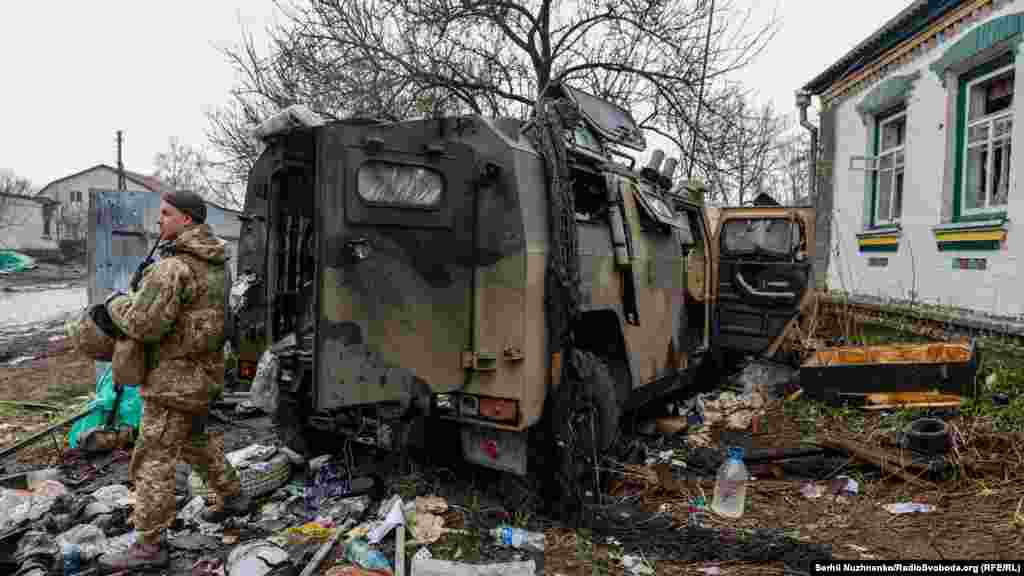 A Ukrainian soldier stands near an abandoned Russian armored vehicle.