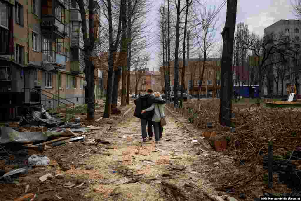Zagrljeni par šeta pored zgrade koja je oštećena u bombardovanju Harkiva, u Ukrajini