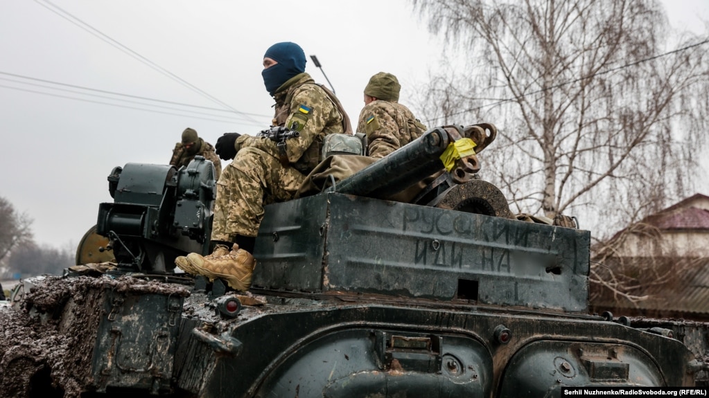 Ushtarët ukrainas duke patrulluar nëpër rrugët e fshatit të shkatërruar.