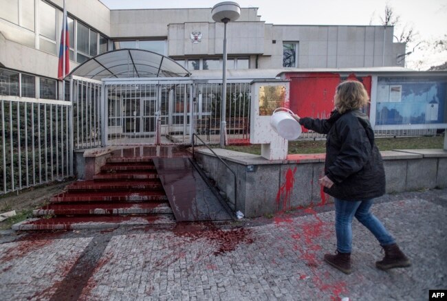 Egy aktivista vörös festékkel önti le a prágai orosz nagykövetség lépcsőjét 2022. március 26-án