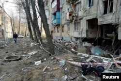A man walks past a residential building hit by a military strike in Kharkiv on April 10.