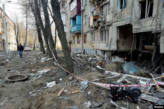 A man walks past a residential building hit by a military strike in Kharkiv on April 10.