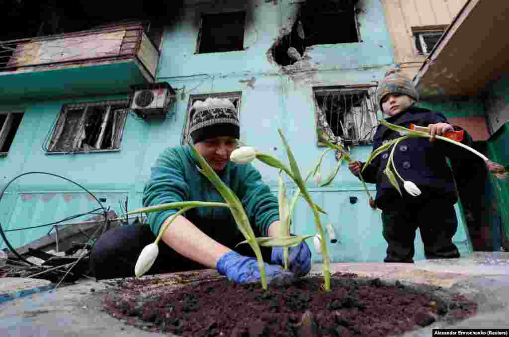 Local resident Viktoria Mukhina plants tulips with her daughter Miroslava near an apartment building damaged by Russian shelling in the southern Ukrainian port city of Mariupol on April 4.