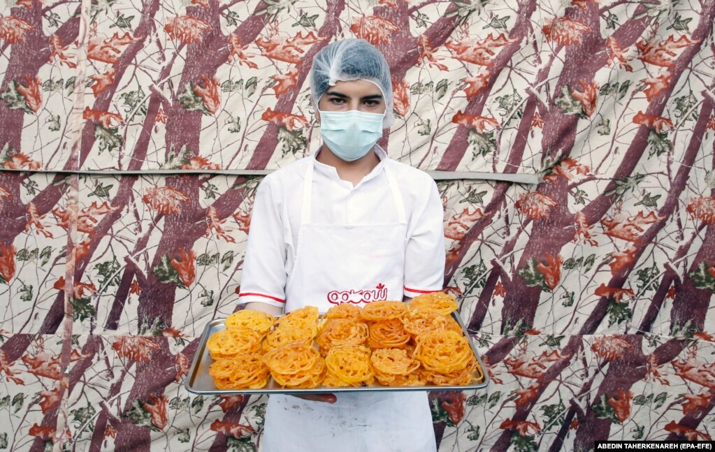 Një punëtore e një dyqani në Teheran mban në duar një tabaka me zoolbia - një ëmbëlsirë e veçantë që shërbehet tradicionalisht për Ramazan.
