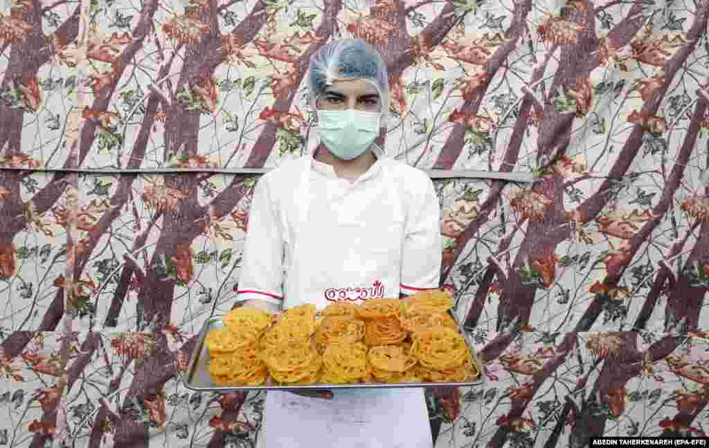 An Iranian worker holds a tray of zoolbia, a special sweet traditionally served for Ramadan, in the kitchen of a sweets shop in Tehran.