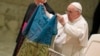 Papa Françesku duke treguar në Vatikan një flamur ukrainas të sjellë nga qyteti i Buça-s.