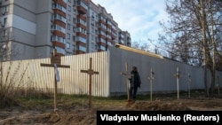 A man stands next to graves with bodies of civilians, who according to local residents were killed by Russian soldiers, in Bucha, outside Kyiv, in April 2022.