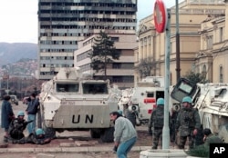 Paqeruajtësit e OKB-së dhe qytetarët e Sarajevës mbulohen nga të shtënat me armë në rrugicën famëkeqe të qytetit që njihej si "Rrugica e snajperëve", mars 1993.