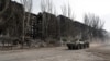 UKRAINE - An armoured vehicle of pro-Russian troops drives along a street past a residential building destroyed during Ukraine-Russia conflict in the besieged southern port city of Mariupol, Ukraine March 31, 2022.