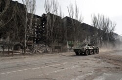 Un vehicul blindat al trupelor pro-ruse, pe o stradă cu clădiri distruse. Mariupol, Ucraina, 31 martie 2022.