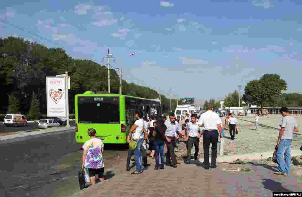 Travelers gather at an increasingly crowded bus stop.