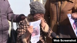 Участница пикета перед консульством Китая Гульпам Казыбек с изображением своей 70-летней матери, задержанной и заключенной в тюрьму в Китае. Алматы, 2 марта 2021 года. 