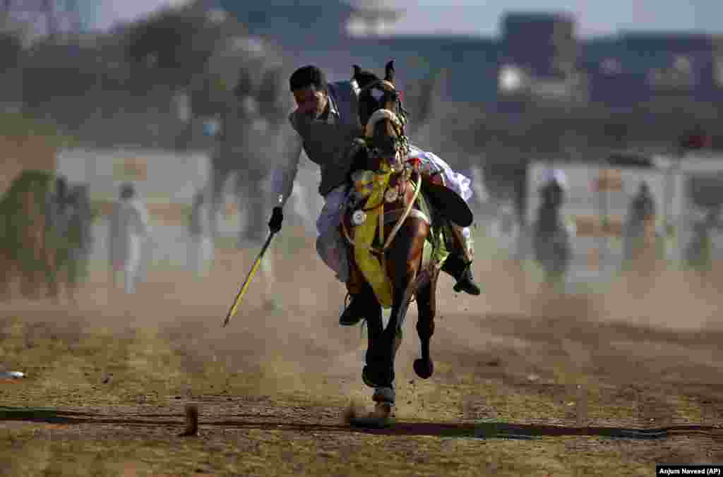 A rider targets a wooden peg during a tent-pegging competition organized by a local club on the outskirts of Islamabad, Pakistan.&nbsp;