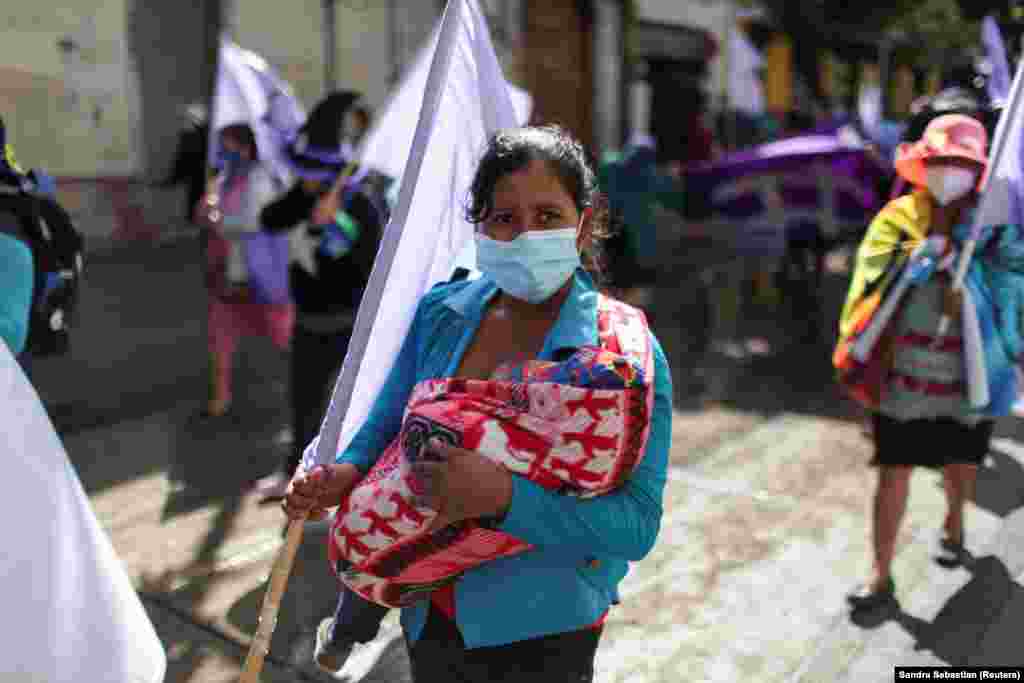 Egy nő a kisbabájával az ölében vesz részt a november 25-i felvonuláson Guatemalában