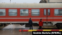 Dy persona qëndrojnë pranë një treni në Fushë Kosovë. 