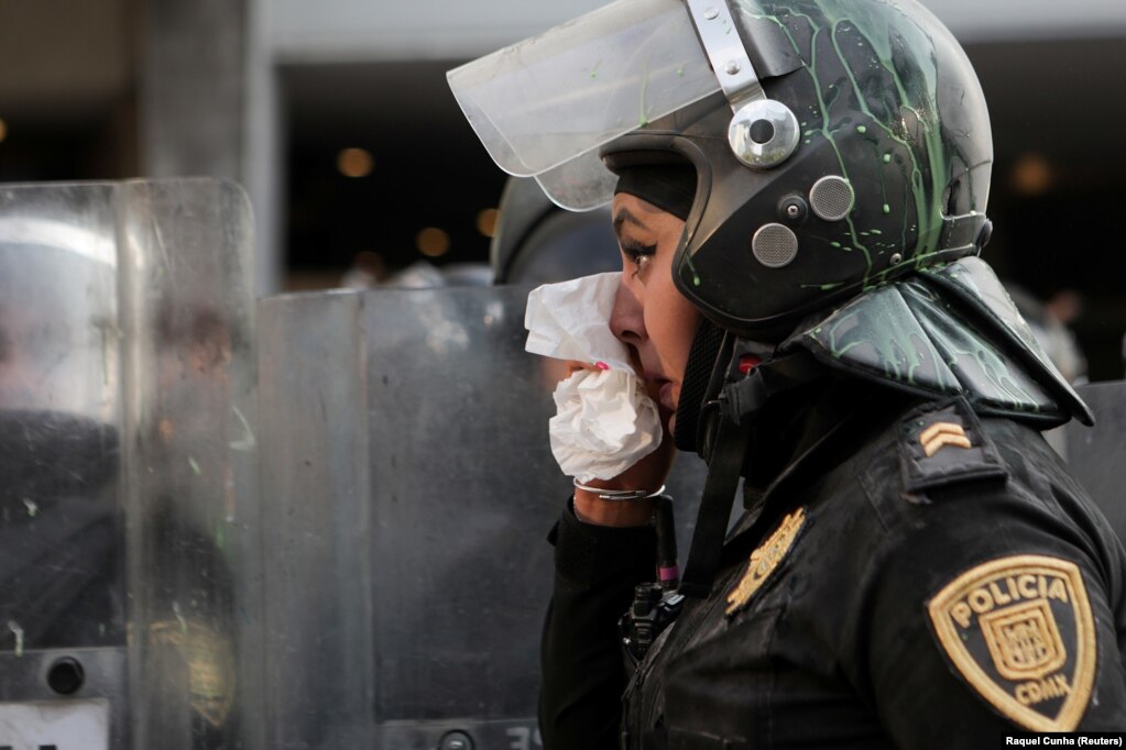Një police duke përdorur një pecetë gjatë një proteste, në Meksiko Siti, Meksikë.