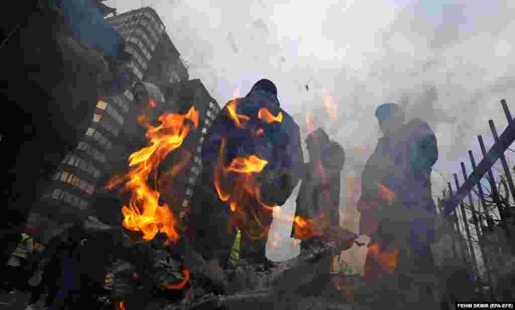 Bosnian miners warm themselves by a fire as they protest measures aimed at transforming their industry in front of the federal government building in Sarajevo on November 23.&nbsp;