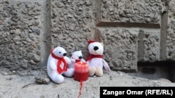 Зажженная свеча и игрушки у места гибели молодой матери и троих ее детей. Алматы, 23 ноября 2021 года