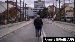 Një qytetar kalon me biçikletë në urën mbi lumin Ibër që ndan Mitrovicën e Jugut dhe atë të Veriut. 