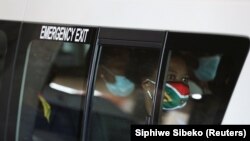 Një grua në një taksi mban maskë me ngjyrat e flamurit të Afrikës së Jugut. Soveto, Afrikë e Jugut, 26 nëntor 2021. 