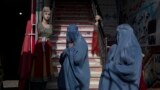 Afghanistan Daily Life -- Burka-wearing Afghan women walk past a clothing shop, in Herat, Afghanistan, Tuesday, Nov. 23, 2021.