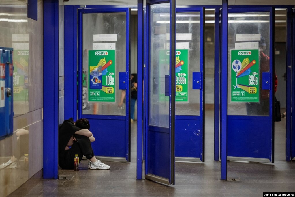 Një grua duke u strehuar pranë portave të një stacioni të metrosë në Kiev, më 9 korrik.