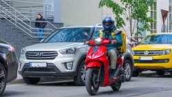 Muncitor străin al unei companii de livrări, transportând o comandă pe o stradă din Chișinău 