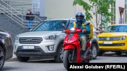 Muncitor străin al unei companii de livrări, transportând o comandă pe o stradă din Chișinău 