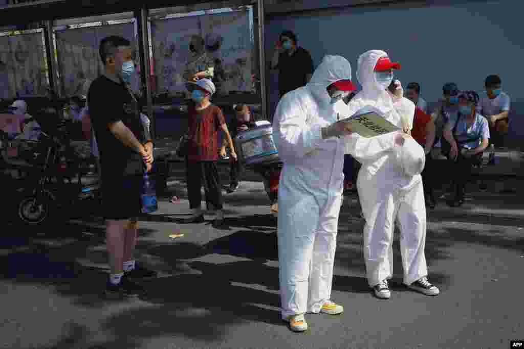Медичні працівники в повному захисному спорядженні стоять біля спортивного центру Гуанан, щоб допомогти людям, які живуть поруч або які відвідали ринок Ксінфаді (гуртовий продовольчий ринок, де з&#39;явився новий спалах коронавірусу COVID-19), пройти тест на коронавірус. Пекін, Китай, 16 червня 2020 року