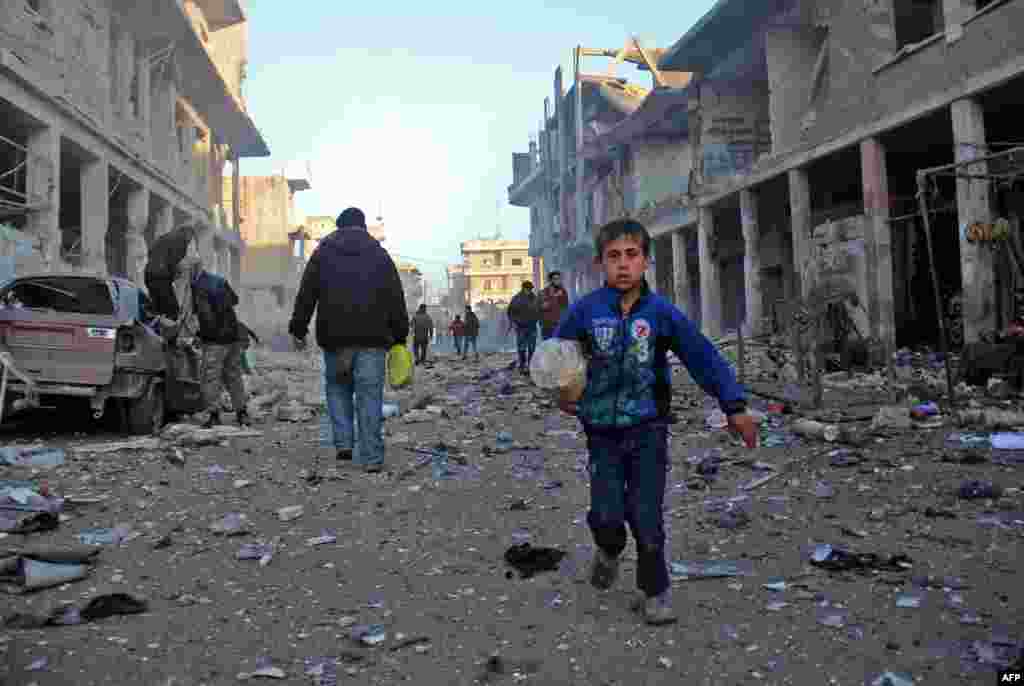 A Syrian boy runs while carrying bread following a reported air strike by government forces in the Syrian town of Binnish, on the outskirts of Idlib. (AFP/Omar Haj Kadour)