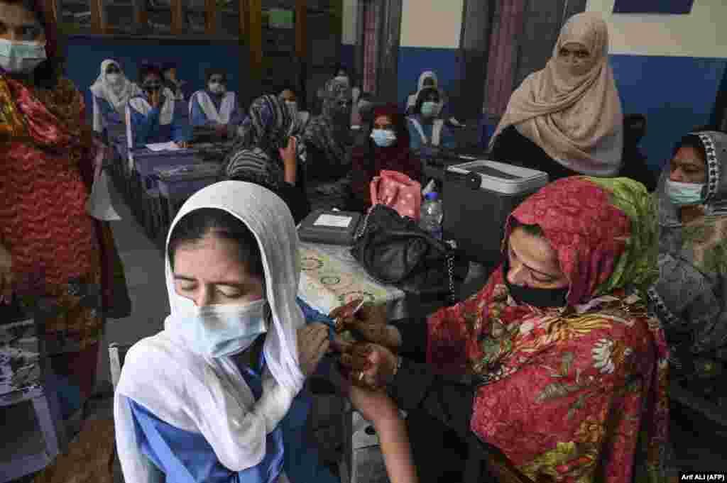 Një punëtore shëndetësore pakistaneze administron një vaksinë kundër COVID-19 ndaj një studenteje në një shkollë në Lahore. Në Pakistan, autoritetet kanë nisur vaksinimin kundër koronavirusit të fëmijëve nga mosha 12 vjeç e sipër.