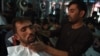 An Afghan barber cuts a customer's hair at a Kabul barbershop prior to the Taliban takeover.