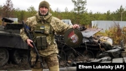 Украински војник го покажува амблемот на елитната единица на руските вооружени сили во близина на уништените руски тенкови во селото Дмитривка, во близина на Киев, на 2 април.