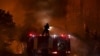 Një zjarrfikës shuan flakët nga maja e një kamioni në fshatin Afidnes, rreth 30 kilometra në veri të Athinës më 5 gusht 2021.