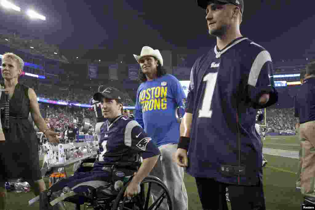 Boston marathon bombing victim Jeff Bauman (left), responder Carlos Arredondo (center), and Taylor Morris (right) of the U.S. Navy are honored in a ceremony before the New York Jets face the New England Patriots in a football game in Foxborough, Massachusetts, on September 12, 2013.