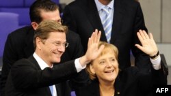 Міністр закордонних справ німеччини Гідо Вестервелле (ліворуч) та канцлер німеччини Ангела Меркель вітають колег з перемогою під час спеціальної сесії парламенту у німецький Бундестаг (нижня палата парламенту) в Берліні, 28 жовтня 2009 року.