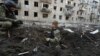 Police officers inspect a crater in front of a damaged residential building hit by a Russian strike in Kharkiv on March 27.