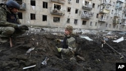 Police officers inspect a crater in front of a damaged residential building hit by a Russian strike in Kharkiv on March 27.