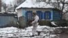 Ukraine -- A soldier walks past an abandoned house