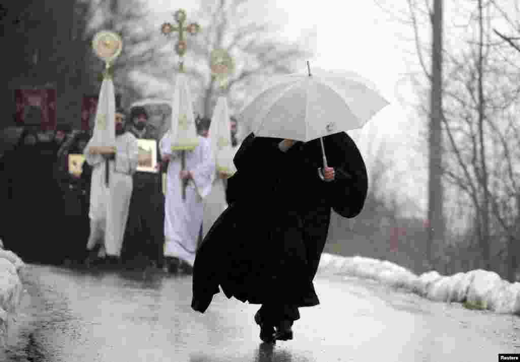 A Macedonian priest, carrying an umbrella, heads a procession during an Epiphany celebration in the village of Bitushe about 150 kilometers west of Skopje. (Reuters/Ognen Teolovski)