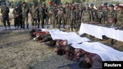 Afghan security forces stand next to the bodies of some of the Taliban insurgents killed by Afghan security forces after the Taliban attacked Kandahar Airfield.