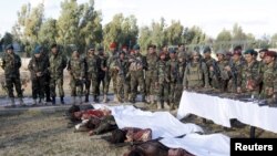 نیروهای دولتی افغانستان بالای سر جنازه شورشیان طالبان که در حمله به فرودگاه قندهار کشته شدند.