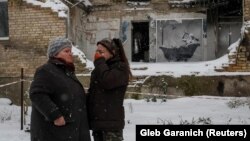Tatyana Reznyicsenko elsírja magát, miközben szomszédjával beszélget Banksy műve előtt Horenkában 2022. november 19-én