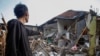 Локален жител стои во близина на куќи оштетени по земјотресот во Цианџур, провинција Западна Јава, Индонезија, 21 ноември 2022 година,