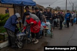 Locuitorii stau la coadă pentru a umple recipientele cu apă potabilă în Herson, sudul Ucrainei, duminică, 20 noiembrie 2022. Forțele ruse au tras cu obuze și rachete asupra orașului Herson, care a fost recent eliberat de forțele ucrainene.