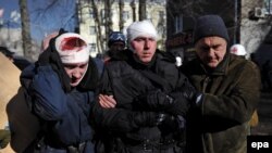 Двое раненых милиционеров идут к машинам скорой помощи в Киеве 18 февраля 2014 года