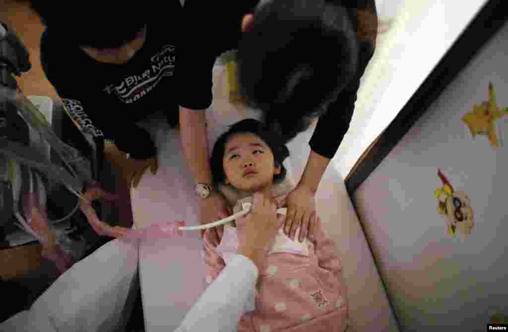 A doctor conducts a thyroid examination on a five-year-old girl as her older brother and a nurse take care of her at a clinic in a temporary housing complex in Nihonmatsu. 