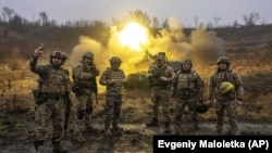 Украинские военные позируют для фото во время ведения огня по российским позициям из самоходной артиллерийской установки на передовой в Харьковской области, 24 декабря 2022 года