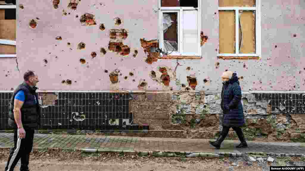 Pleșan dă binețe unei vecine în fața uneia din casele de la Izium avariate de război. Orașul, care avea cândva 45.000 de locuitori, a fost eliberat de sub ocupația rusă în septembrie 2022. &nbsp;